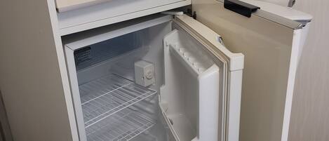 A compact refrigerator with a freezer compartment, built-in ice maker, and a water dispenser.