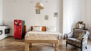 A room with a bed, a wooden coffee table, a red refrigerator, a vintage radio, and a patterned armchair. - Nice apartment with WiFi in charming T'bilisi (T'bilisi)