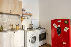 A compact kitchen with a washing machine, a stove, and a red refrigerator.