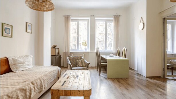 A room with a bed, a wooden coffee table, a dining table with chairs, and large windows with curtains. - Nice apartment with WiFi in charming T'bilisi (T'bilisi)