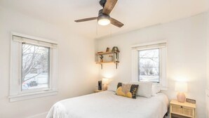 Una camera da letto con un letto, due comodini, una ventola a soffitto e due finestre.