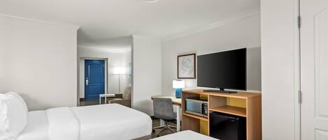 Une chambre d’hôtel avec deux lits, un bureau avec un ordinateur, une télévision et un four à micro-ondes.