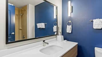 A modern bathroom with a large mirror, white sink, and blue walls.