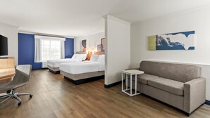Een hotelkamer met twee bedden, een bank, een bureau en een televisie.