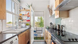 A compact kitchen with a washing machine, a sink, and a stove.