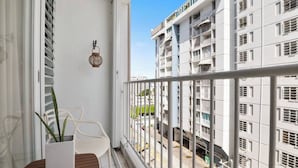 A balcony with a white railing, a wooden table, two white chairs, and a potted plant. - Studio 3 minutes to the airport| Free Parking|Pool (Carolina)