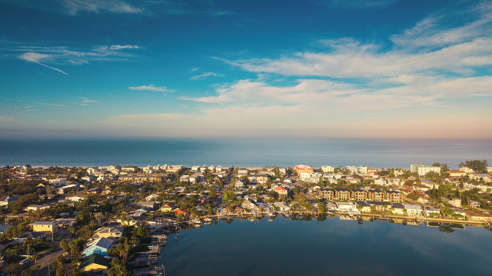 A coastal town with a marina, residential buildings, and a clear view of the ocean.