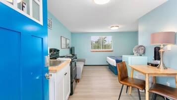 A compact room with a kitchenette, a bed, a desk, and a chair.