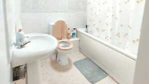 Een badkamer met toilet, wastafel en bad.