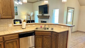 Cocina con gabinetes de madera, lavavajillas, fregadero y luces colgantes.
