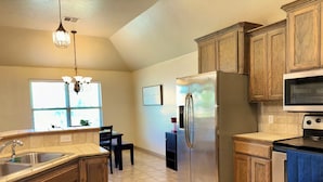 Una cocina con armarios de madera, un refrigerador de acero inoxidable, un microondas y una estufa.