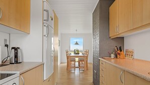 Une cuisine moderne avec des meubles en bois, un four encastré et un coin repas comprenant une table et des chaises.
