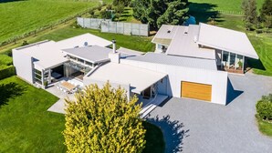 A modern house with a large garage, a covered patio, and a well-maintained lawn.