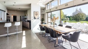 A modern kitchen with a dining area, large windows, and a view of the outdoors.