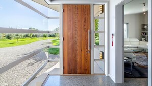 A modern interior with a wooden door, a glass wall, and a view of greenery outside.