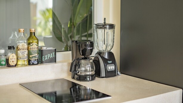Una encimera de cocina con una licuadora, una cafetera y varias botellas.