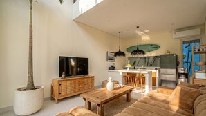 A modern living room with a large sofa, a coffee table, a TV, a wooden cabinet, and a potted plant. - Villa Pia Pererenan (Munggu)