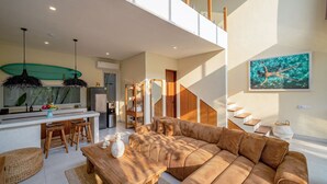 A modern interior with a kitchen, dining area, and living room, featuring a staircase and a large window. - Villa Pia Pererenan (Munggu)