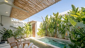 A poolside area with a pool, lounge chairs, and tropical plants. - Villa Pia Pererenan (Munggu)