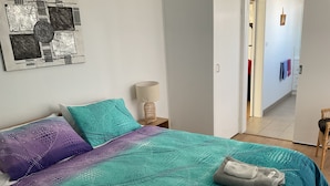 A bedroom with a bed, pillows, a nightstand, and a lamp. - Seaduce, only 300m to the beach! (St Leonards)