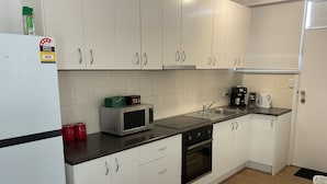 A modern kitchen with white cabinets, a microwave, a coffee maker, and a sink. - Seaduce, only 300m to the beach! (St Leonards)