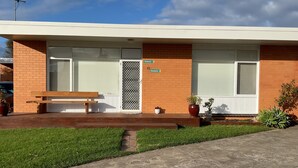 A building with a brick facade, a wooden bench, and a small garden area with potted plants. - Seaduce, only 300m to the beach! (St Leonards)