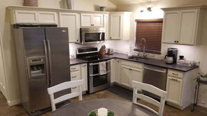 Una cocina compacta con armarios blancos, electrodomésticos de acero inoxidable y una mesa redonda con un centro de mesa.