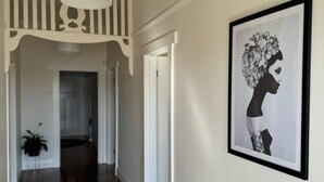 A hallway with wooden flooring, a grey rug, a white ceiling light, and a framed black and white artwork on the wall. - 11Eardley|5min to CBD | 2 Bedrooms | Free parking (South Launceston)