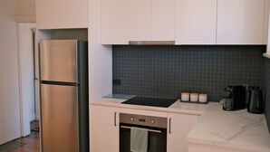 A modern kitchen with stainless steel appliances, a black backsplash, and a countertop with jars labeled "Sugar," "Coffee," and "Tea." - 11Eardley|5min to CBD | 2 Bedrooms | Free parking (South Launceston)