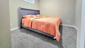 Een slaapkamer met een bed, vloerbedekking en een raam met zonwering.