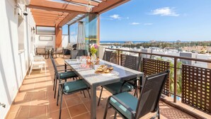 Un balcón con mesa lista para comer, sillas y vistas de la ciudad.