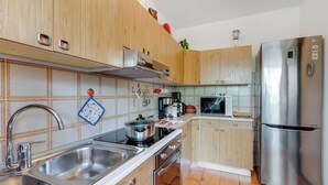 A modern kitchen with stainless steel appliances, wooden cabinets, and a tiled backsplash.