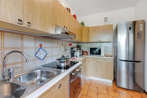 A modern kitchen with stainless steel appliances, wooden cabinets, and a tiled backsplash. - Dora - Riva del Garda Apartment with Terrace, Riva del Garda, Italy (Riva del Garda)
