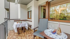 A balcony with a table set for two, a chair, and a bottle of champagne.