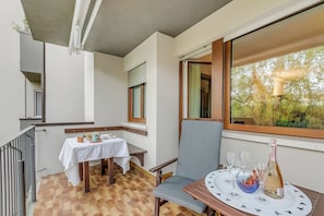 A balcony with a table set for two, a chair, and a bottle of champagne. - Dora - Riva del Garda Apartment with Terrace, Riva del Garda, Italy (Riva del Garda)