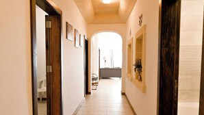 A hallway with a tiled floor, wooden doors, and framed pictures on the walls. - Sea & Valley Views Żebbuġ Gozo, Żebbuġ Gozo, Malta (Żebbuġ Gozo)