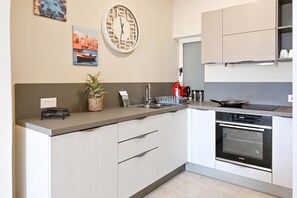 A modern kitchen with a built-in oven, a sink, and a countertop with a plant and a kettle. - Sea & Valley Views Żebbuġ Gozo, Żebbuġ Gozo, Malta (Żebbuġ Gozo)