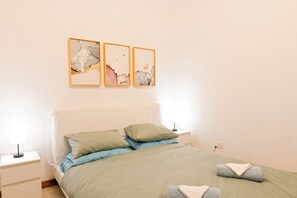 A bedroom with a bed, pillows, a nightstand, and wall art.