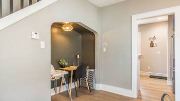 Una cocina moderna con estufa integrada, un comedor con mesa y sillas, y una escalera que conduce a otro nivel.
