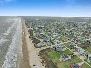 An aerial view of a coastal residential area with houses, a beach, and a water tower.