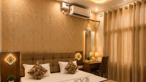 Une chambre d’hôtel avec un grand lit, un ventilateur de plafond, un appareil de climatisation, un bureau avec une chaise et un grand miroir.