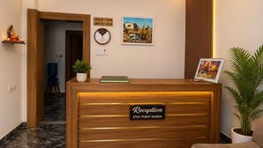 Un comptoir d’accueil avec une horloge, un tableau encadré et un panneau indiquant les heures d’arrivée et de départ.