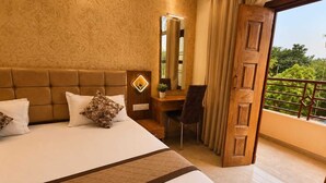 Une chambre d’hôtel avec un grand lit, un bureau, une chaise, un miroir et un balcon doté d’une rambarde.