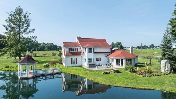 A large white house with a red roof, a gazebo, and a pond reflecting the structure. - Amish Country Getaway w/ Hot Tub & Views (Applecreek)