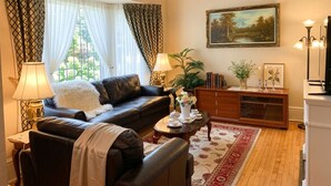 A living room with a sofa, a coffee table, a lamp, a painting, and a cabinet. - Private Room Honey Room 15 MINS WALK to Falls (Niagara Falls)