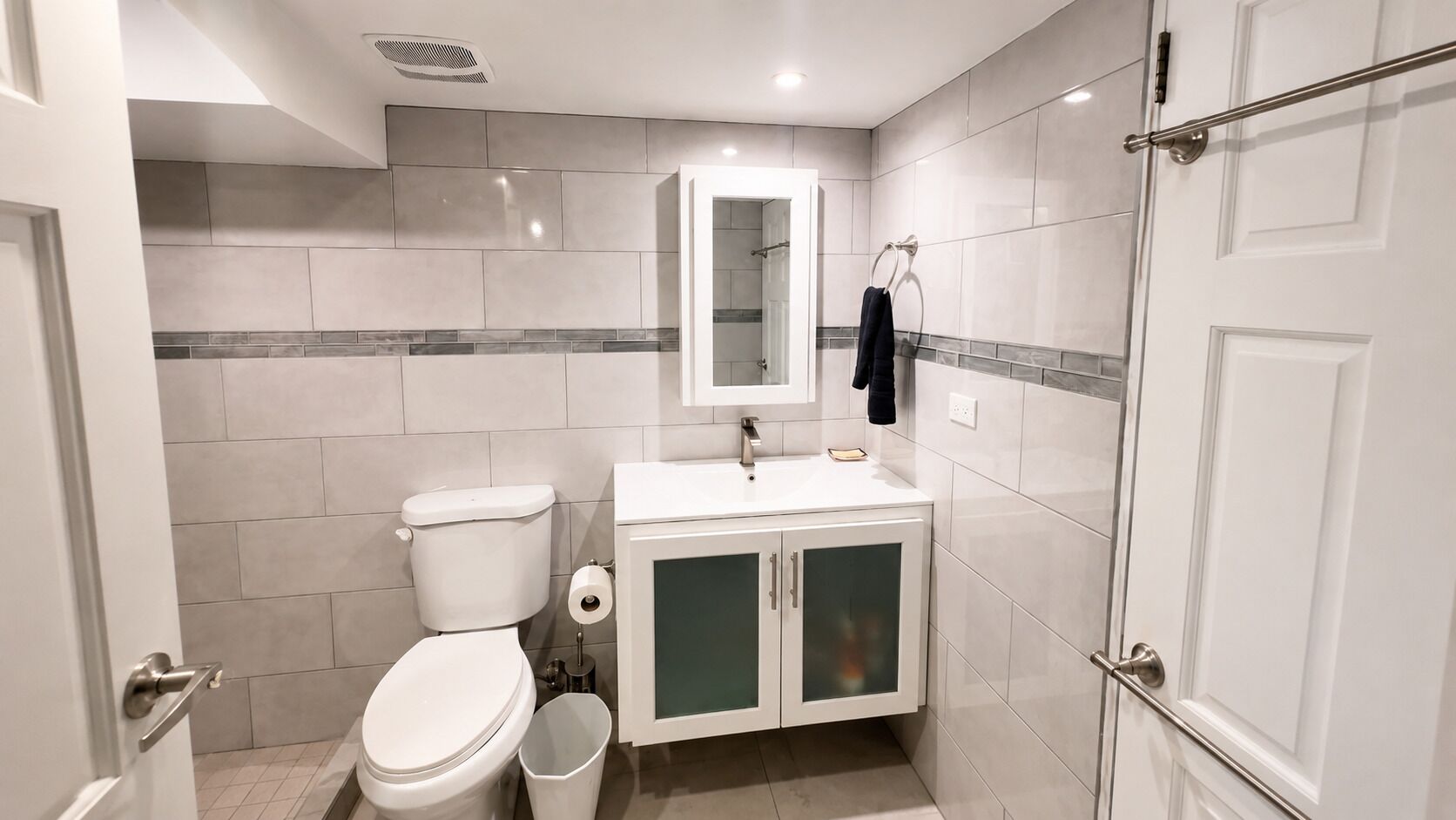 Une salle de bain équipée de toilettes, d’un lavabo, d’un miroir et d’un porte-serviettes.