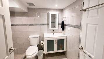 Une salle de bain équipée de toilettes, d’un lavabo, d’un miroir et d’un porte-serviettes.