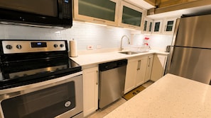 A modern kitchen with stainless steel appliances, white cabinetry, and a granite countertop.