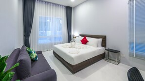 Une chambre d’hôtel moderne avec un lit bien fait, un canapé, une petite table d’appoint et une plante en pot.