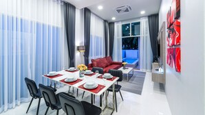 Une chambre d’hôtel moderne avec un coin repas, un canapé rouge et un téléviseur.